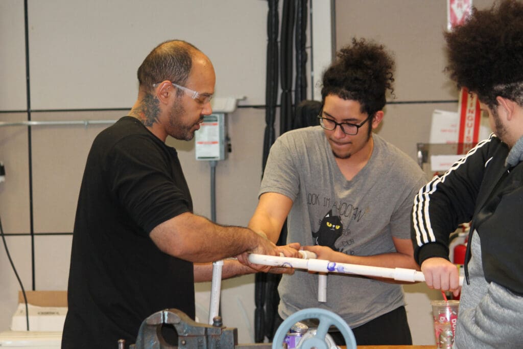 Students working on pipes of an HVACR system